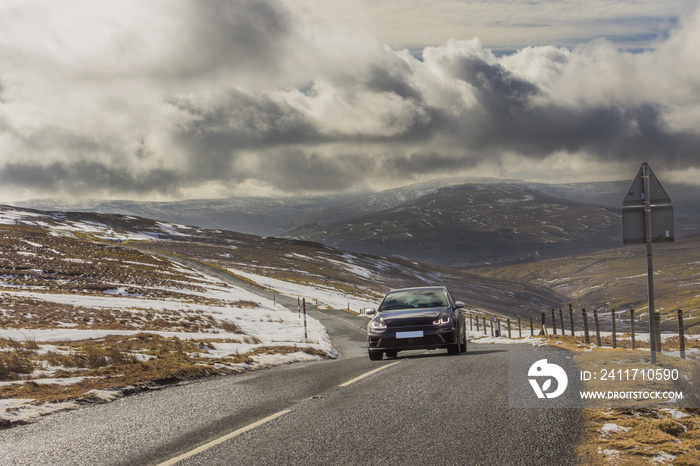 A car travelling down the dramatic and winding Buttertubs Pass Yorkshire Dales