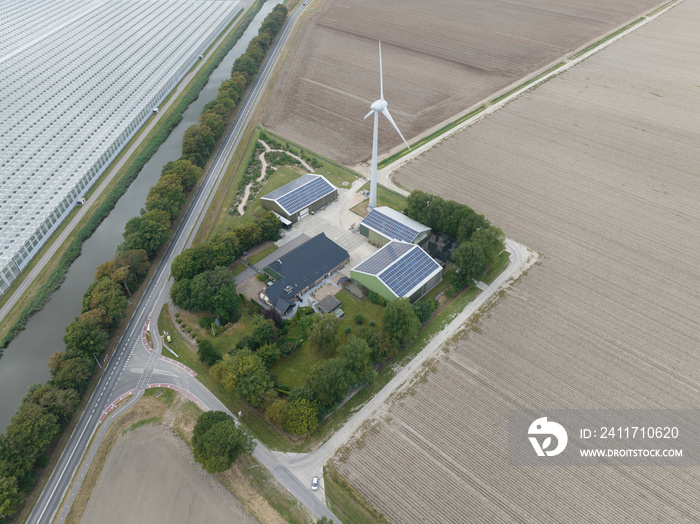 Modern agriculture farm with solar panels and wind turbine for electricity generation company. House home and business in food production. Aerial drone view.