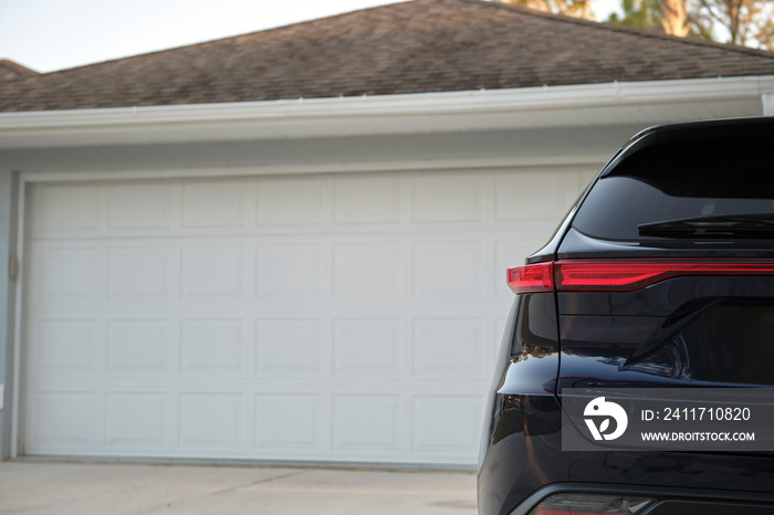 Car parked in front of wide garage double door on concrete driveway of new modern american house