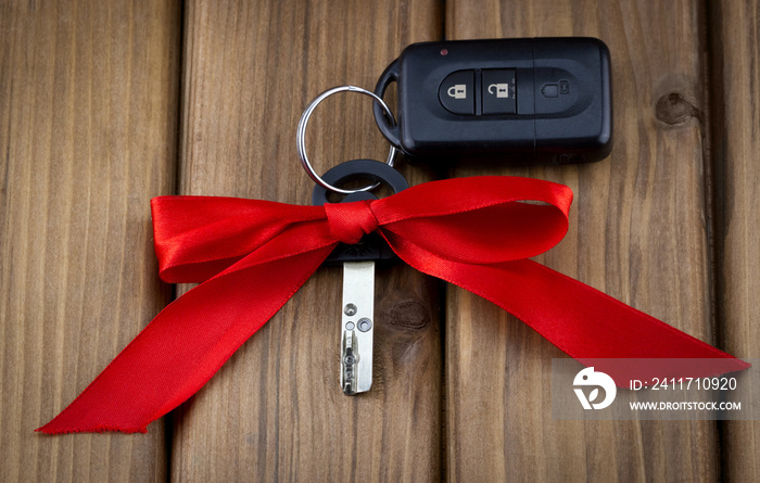 Close-up view of car keys with red bow as present on  wooden background