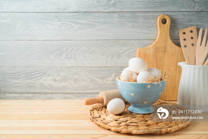 Easter baking background with eggs and kitchen utensils on wooden table