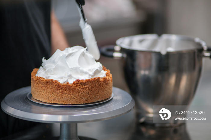 pastry chef designer filling a pie crust with lemon flavour meringue mousse cheese cream with spatula