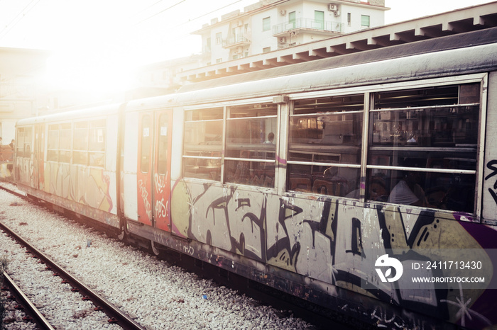 A train with closed doors waiting for passengers at the railway station. Street art and urban culture painted on the tube, Sunlight in background