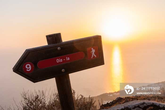 Oia trail walking sign with the sunrise and sea in the background