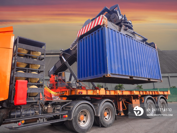 The reach stacker is lifting 20’ container from truck to storage area for stuffing cargo in container at industrial warehouse.