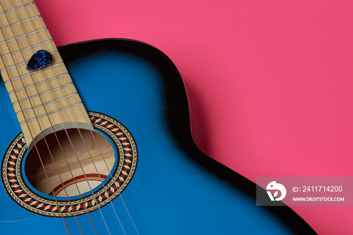 Classic blue and black wooden guitar on colored background. With strings golden and transparent strings. Guitar nib in blue and black color.