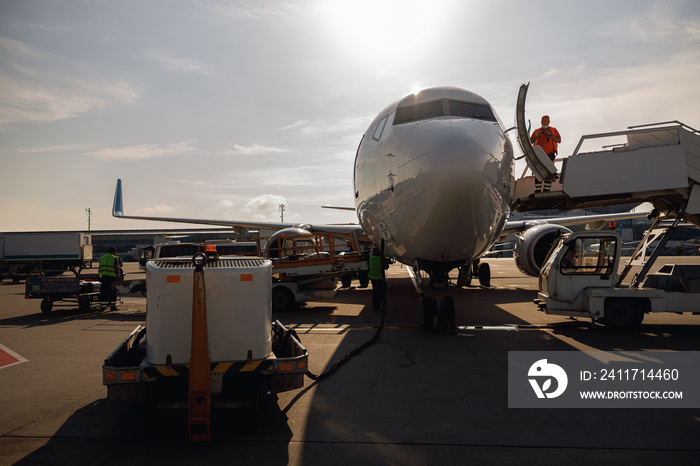 People standing near big modern airplane, preparing it for boarding in airport hub on a daytime. Plane, shipping, transportation concept