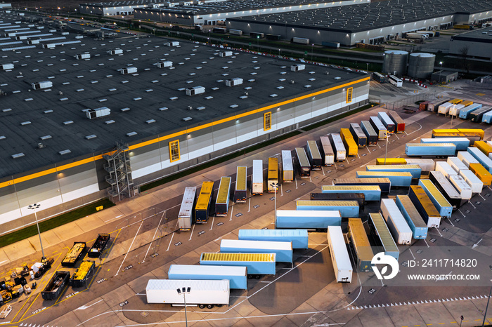 Top view of many trailers and containers near the logistics warehouse, in the evening