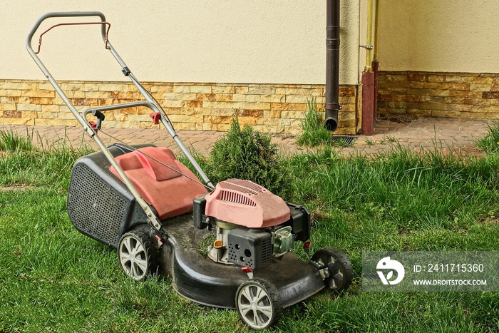 one lawn mower on the green grass near the wall of the building