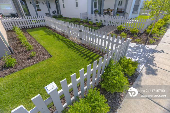 Front yard with lawns and shrubs with white fence