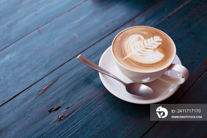 Cup of Hot Cappuccino coffee with fresh milk Art’s surface floating on top . on rustic wooden background and copy Space