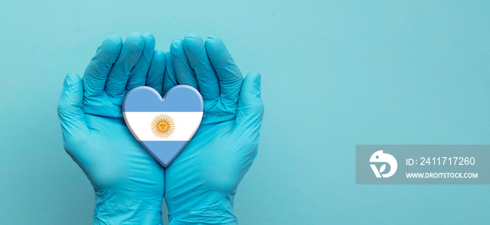 Doctors hands wearing surgical gloves holding Argentina flag heart