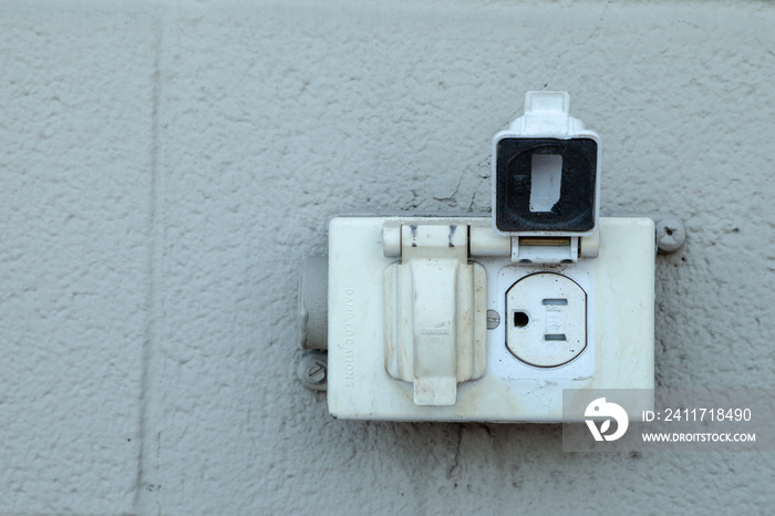 Old rustic North American electrical outlet on a exterior grey brick wall