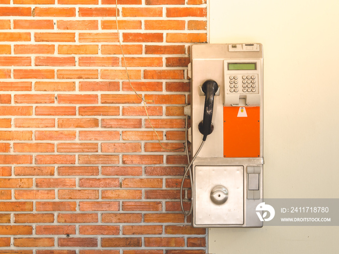 An old public payphone with red brick wall at the university in Thailand.