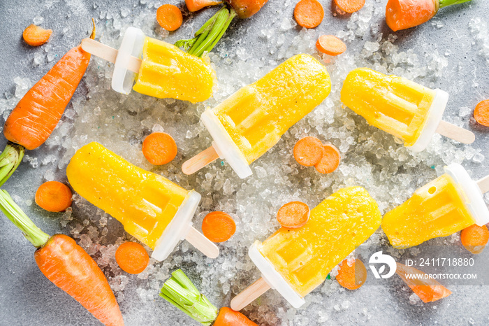 Vegetable gelato. Vegan carrot ice cream popsicles with organic baby carrots, old rustic wooden background.