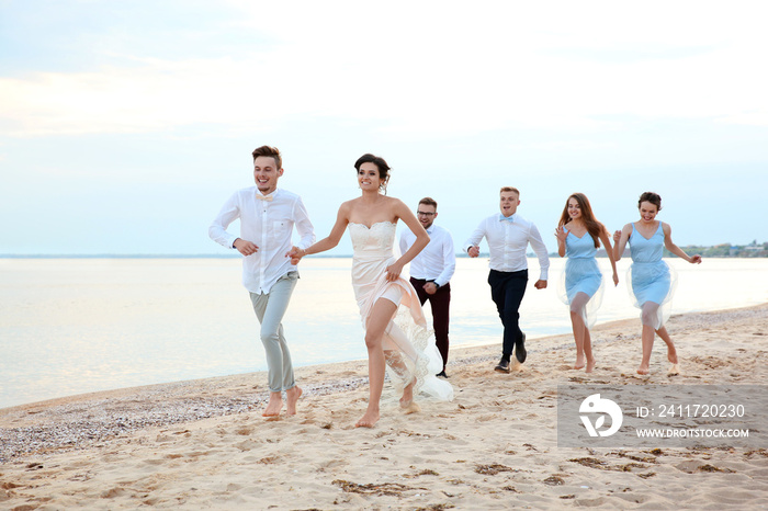 Happy wedding couple having fun with friends on beach