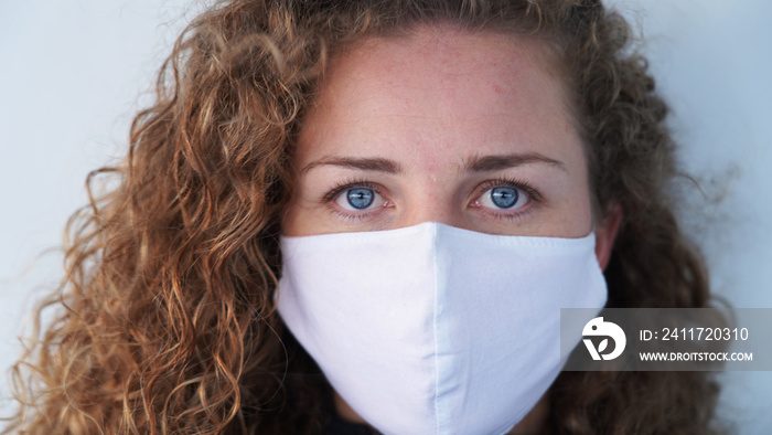 beautiful blond-haired curly girl in a medical mask on a light background. Serious blue-eyed girl in a respirator. safety from diseases. respiratory disease prevention. cruise ship