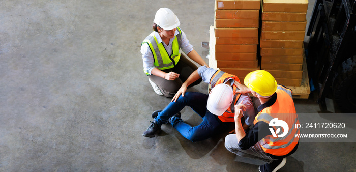 Top view. First Aid and safety first. Engineering talking on walki talki radio to employee while his warehouse coworker lying unconscious at industrial factory. Health insurance emergency accident.