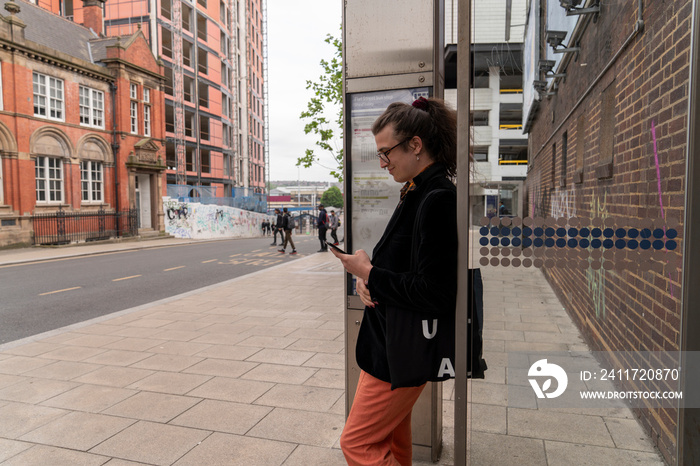 Young man using phone while waiting at bus stop