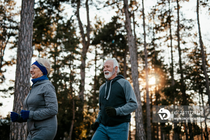 An older married couple jogging together on a beautiful sunny winter day.