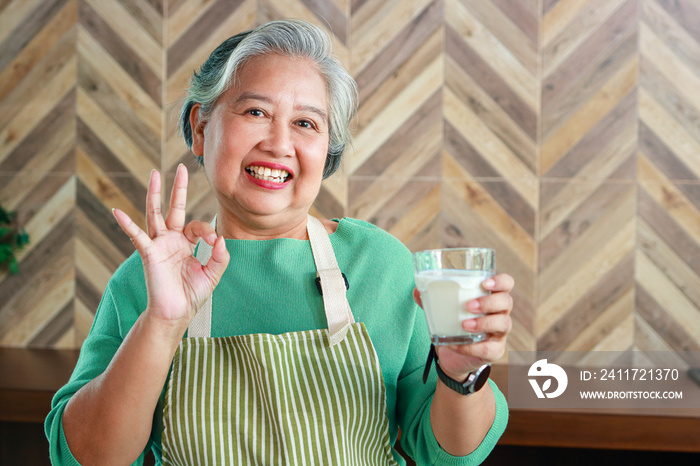 Asian old woman in good health smiling brightly holding a glass of skim milk Ready to make a thumbs up ok. nutritious food for the elderly