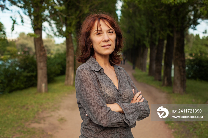 Mature woman walking in summer park outdoors