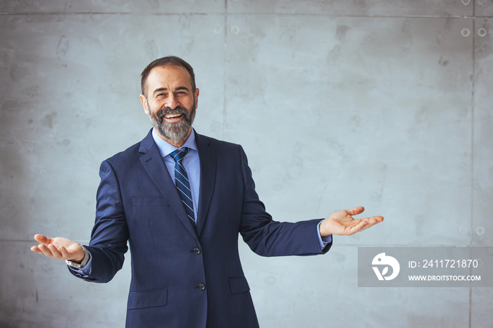 Mature businessman portrait. Successful businessman posing with crossed arms and smiling at camera. Good-looking middle-aged businessman with arms crossed isolated in gray background