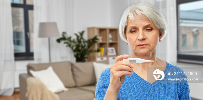 health, old age and people concept - sick senior woman with thermometer over home living room background