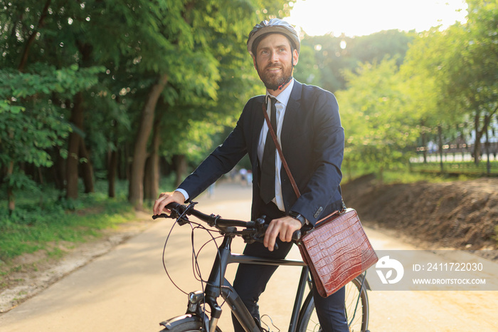 Male manager in suit, riding on bike, while getting to workplace.