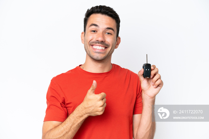 Young handsome man holding car keys over isolated white background with thumbs up because something good has happened