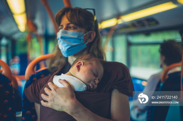 Mother with baby in sling wearing face massk on the bus