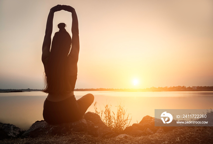 Silhouette Asian woman practicing yoga at sunset