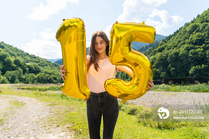 Teenage girl holding golden balloon with number 15th