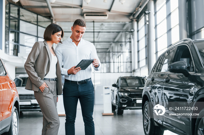 Making agreement. Man in formal wear helping customer with choice of the automobile