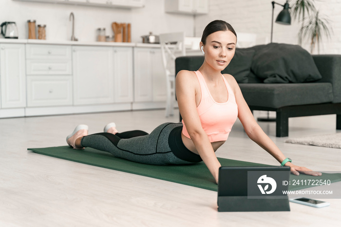 Jolly female watching tablet during home workout stock photo