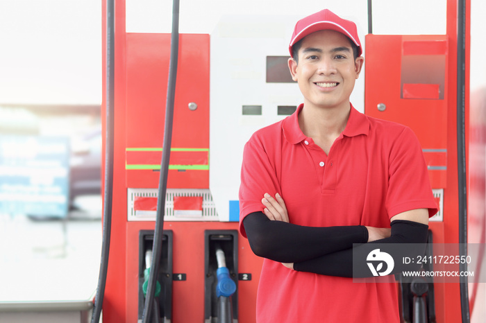 Portrait of happy smiling Asian gas station attendant in red uniform standing with crossed arms at gas station.