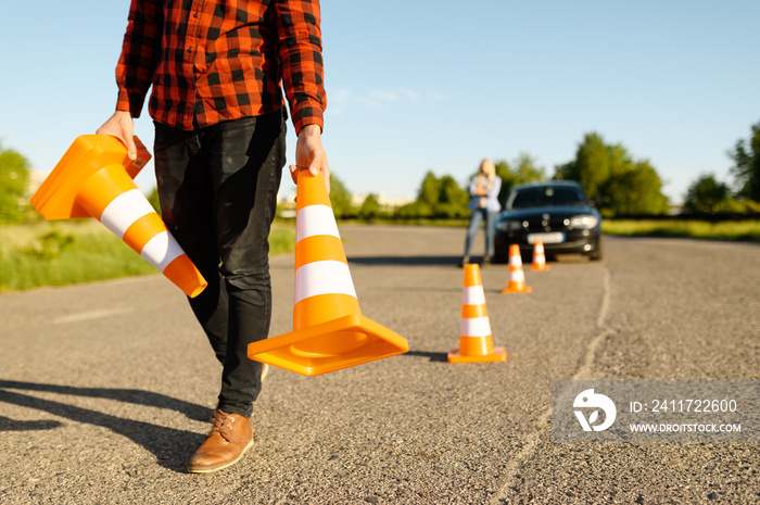 Male instructor puts cones on road, driving school