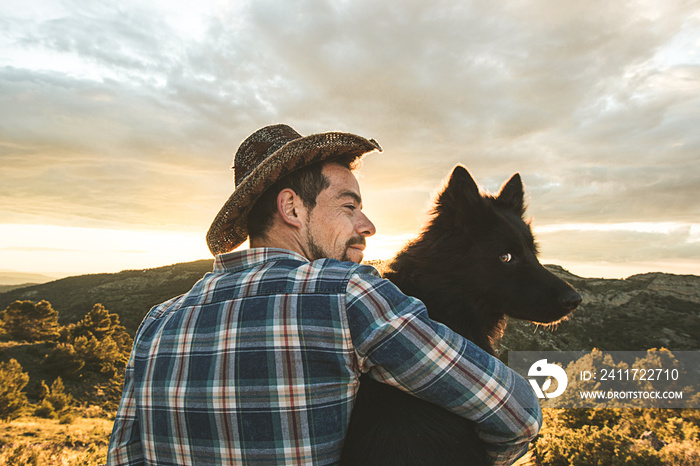 Man hugging his dog at sunset. Concept of love between man and dog