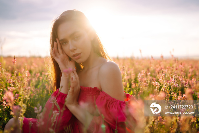 Young  woman in pink dress in the blooming field. Summer landscape. Fashion, style concept.