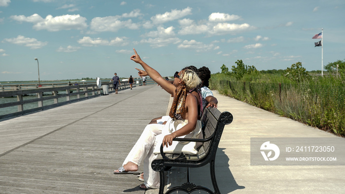 USA, Family relaxing on bench on pier