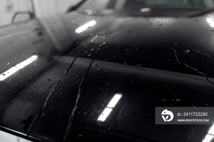 Drops of water on hood of black car after washing