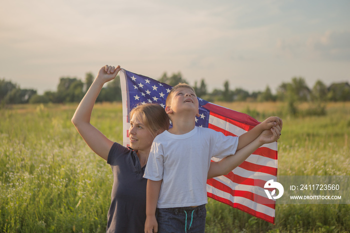 Little boy lets the american flag fly in his hands on the wind at the green field. Patriotic family celebrates usa independence day on 4th of July. Constitution and Patriot Day.