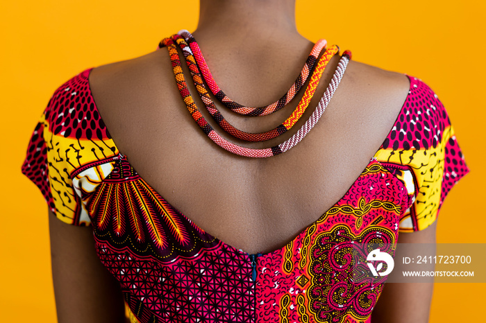 A red necklace on black leather, and a red traditional t-shirt. Details of African style on a bright background.