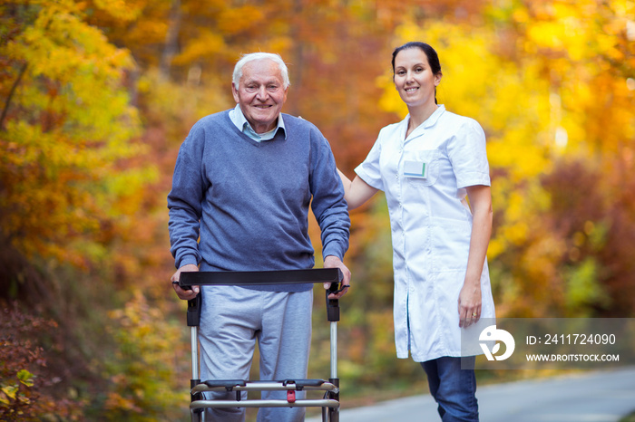 Nurse helping elderly senior man. Senior man using a walker with caregiver outdoor