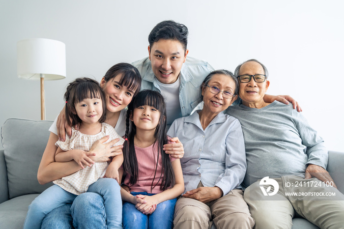 Portrait of Asian happy family sit on sofa and smile, look at camera.