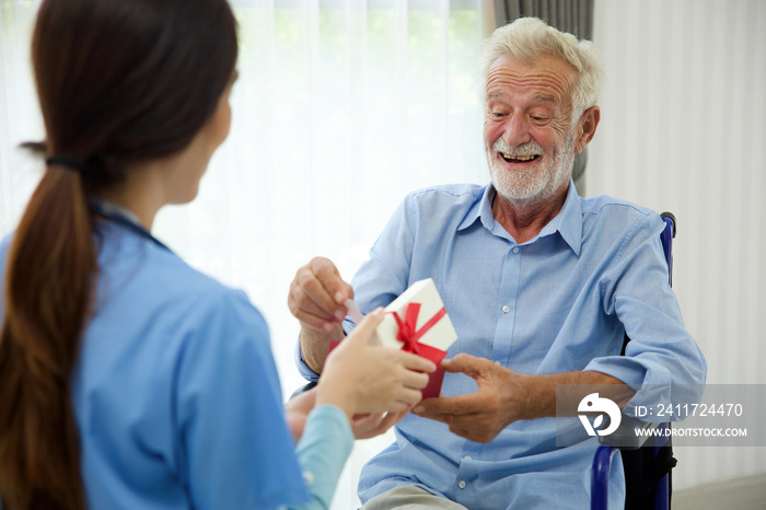 senior man taking a gift box from caregiver for happy birthday