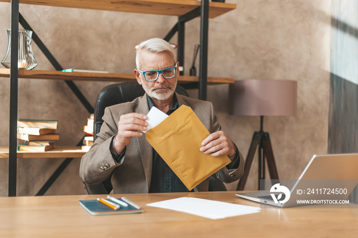 The court’s decision. A mature man opens an envelope with documents at the table in the office. Business communication, service message.