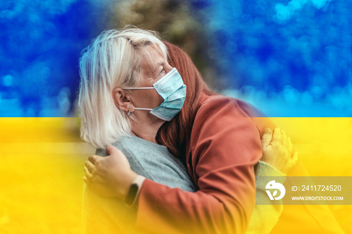 Support for Ukraine. No war. Two women hugging in the park. Mother and daughter with protective surgical face mask. Population migration