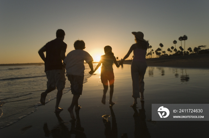 Parents with children holding hands and running on beach