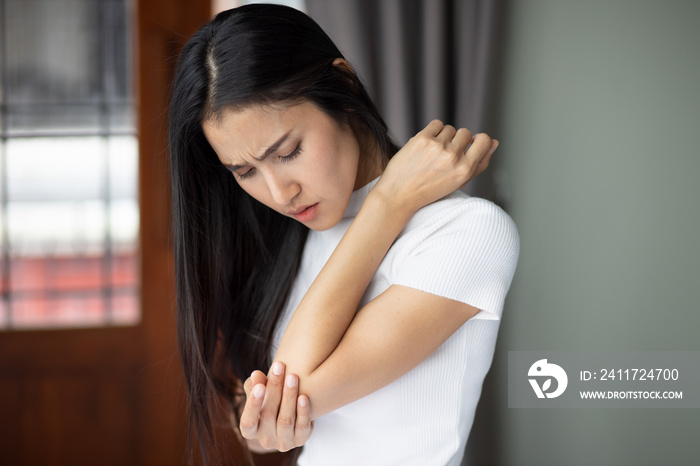 Asian woman suffering from tennis elbow syndrome, pain from elbow injury